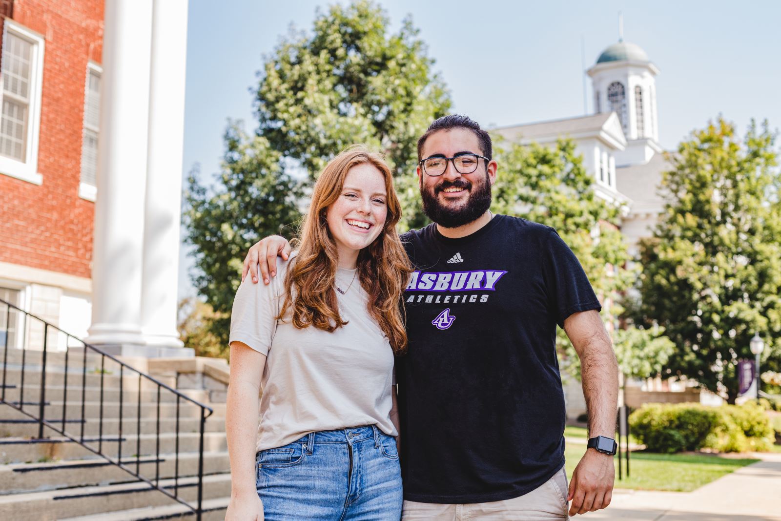 two students smiling in front of campus building